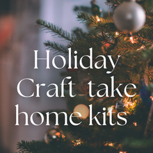 Load image into Gallery viewer, A decorated Christmas tree with lights and take-home craft kits sign text placed in front.