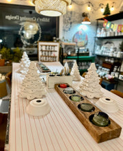Load image into Gallery viewer, Decorative items including ceramic Christmas trees and a wooden candle holder with candles on a table.
